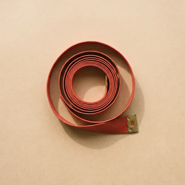 Zinnoberrotes Massband aus Leinen, locker aufgerollt, mit Messingklemme